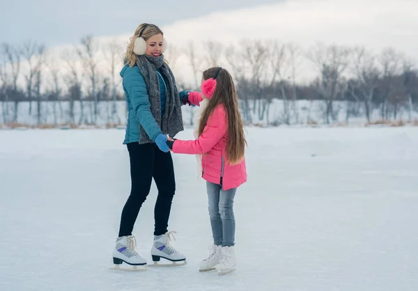 Giovani famiglie si divertono nella zona ghiacciata in un parco innevato — Foto Stock