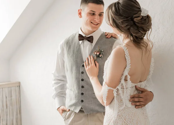 Noiva em vestido branco e noivo em terno, posando no estúdio branco — Fotografia de Stock