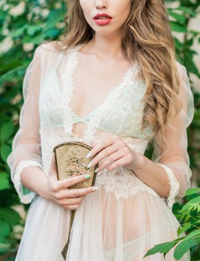 Dalgalı siyah saçlı beyaz dantelli bir gelinin portresi.