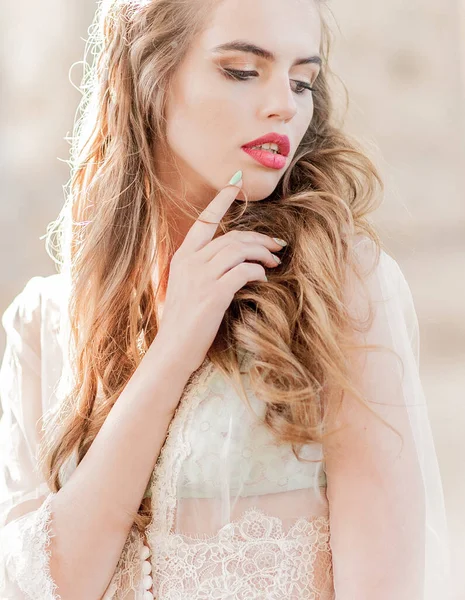 Dalgalı kıvırcık saçlı beyaz dantelli bir gelinin portresi.