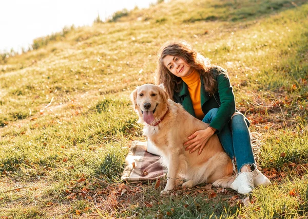 在阳光明媚的日子里 一只金黄色的猎犬和一个卷曲的女人在户外散步 在公园里训练狗 爱和照顾宠物 背景色 — 图库照片
