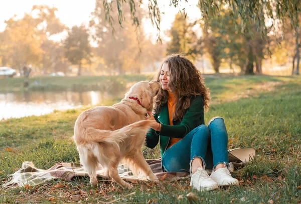 笑着的女人抱着她心爱的金发碧眼的猎犬靠近脸 金毛猎犬和卷曲的女人在室外阳光明媚的日子里玩耍 爱和爱护宠物 — 图库照片