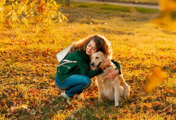 笑着的女人抱着她心爱的金发碧眼的猎犬靠近脸 金毛猎犬和卷曲的女人在室外阳光明媚的日子里玩耍 爱和爱护宠物 — 图库照片