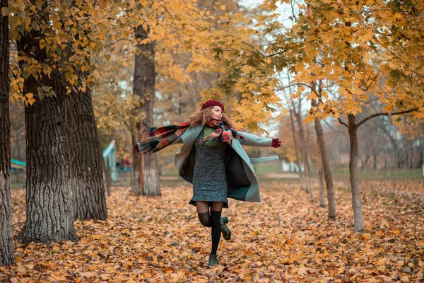 Meisje wervelt rond het verlaten herfst gele bladeren in warme kleding — Stockfoto