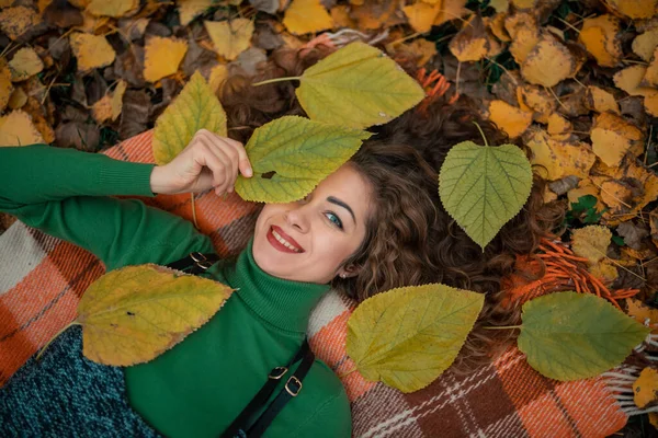 Belle fille liyng sur les feuilles d'automne et regarde la caméra avec un sourire — Photo
