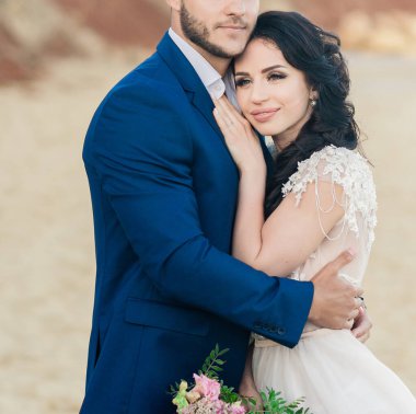 Düğün genç gelin ve damadın yakın plan portresi. Eski katedralin yanında poz veriyorlar. Balayı çifti düğün günü öpüşüyor, mutlu çift aşık, düğün öpücüğü