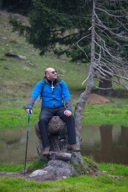 Yürüyüşten sonra göl kenarında oturup dinlenen bir adam.