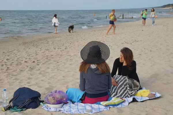 Las mujeres se sientan en la arena en la playa de la ciudad — Foto de Stock