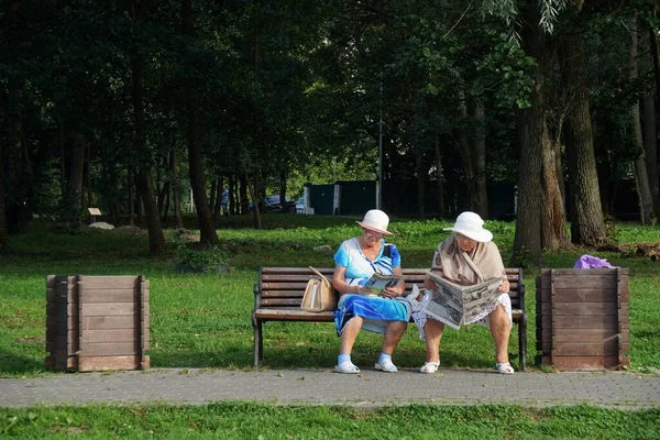 Two elderly women in the park read newspapers — Stock Photo, Image