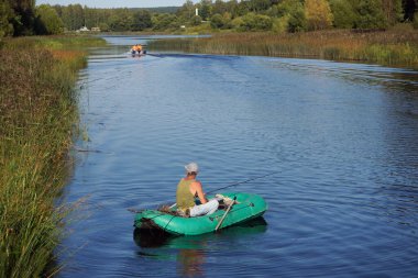 Shuya. Teze nehrinde lastik bir teknede olta taşıyan balıkçı.
