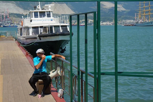 Um homem no porto convida para um passeio marítimo em um navio . — Fotografia de Stock