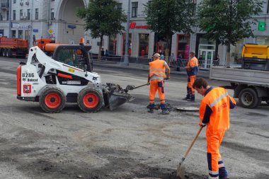 Kürekli işçiler eski asfaltı kaldırıp arabaya yüklüyorlar.