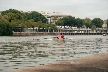 Seville, İspanya; 2 Şubat 2025: Sevilla 'da Guadalquivir Nehri' nde kürek çeken iki kadın. Seçkin sporcular Guadalquivir Nehri 'nde antrenman yapıyor..