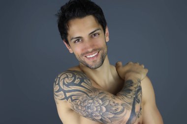 poz gülümseyen yakışıklı. Çekici dövmeli erkek model gri 