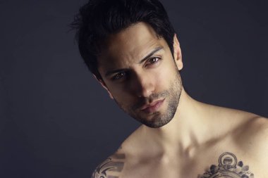 Stüdyo portre yakışıklı genç adamın gri bir arka plana dayanır