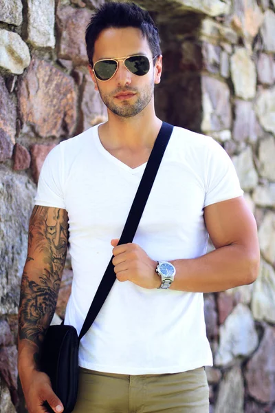 Fashionable man wearing satchel bag, watch ans sunglasses . Summer clothes for men