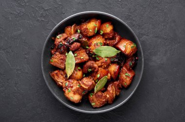 Siyah kaseli Adobo Pork. Geçmişi karanlık. Domuz Adobo ya da Adobong Baboy filipino mutfağı olup domuz eti, defne yaprağı, soya sosu, sirke ve baharatlarla pişirilir. Filipin yemeği. Üst görünüm
