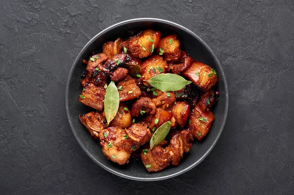 Siyah kaseli Adobo Pork. Geçmişi karanlık. Domuz Adobo ya da Adobong Baboy filipino mutfağı olup domuz eti, defne yaprağı, soya sosu, sirke ve baharatlarla pişirilir. Filipin yemeği. Üst görünüm