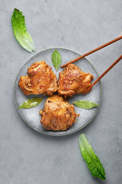 Filipinli Tavuk Adobo gri plakalı beton zemin üzerinde. Tavuk Adobo, pişirilmiş tavuk budu, soya sosu, sirke, karabiber ve defne yapraklarından oluşan Filipin mutfağı tabağıdır. Filipin yemeği. Üst görünüm