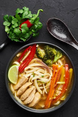 Thukpa tavuğu siyah kasede, arka planda. Thukpa tavuğu, sebzeli ve tavuk etli Tibet erişte çorbası. Üst görünüm