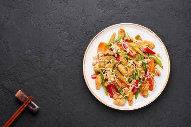 Beyaz plakalı Chicken Chop Suey, arka planda. Chop Suey, farklı kızarmış sebzeler, tavuk eti ve soslarla karıştırılmış Amerikan Çin mutfağı. Uzayı kopyala Üst Manzara. Amerikan yemekleri..