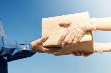 Lastik eldivenli teslimatçı müşteriye bir paket verir. Karantinada teslimat servisi. Covid-19 salgınının etkisi.
