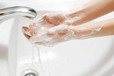 Beyaz lavaboda el yıkama. Sabunlu kadın ellerindeki musluktan su akar. Covid-19 koronavirüs koruyucu önlem.
