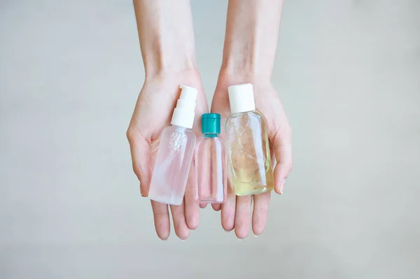 Three hands sanitizer in female hands. Woman keeps in palms several antiseptic bottles.