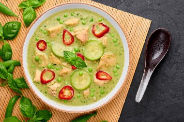 Tay yeşili körili tavuk ya da beyaz kasede siyah arka planda Gaeng Kaew Wan Gai. Tayland yeşil köri yeşil biber, fesleğen, hindistan cevizi sütü, sebze ve baharatlı Tayland mutfağıdır.