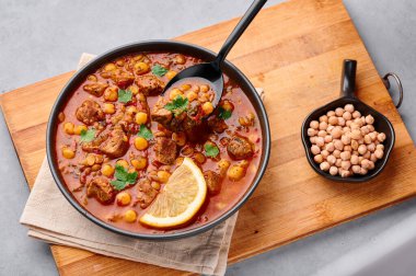 Fas Harira Çorbası, gri beton masa üstünde siyah kâsede. Harira, kuzu eti, et, nohut, mercimek, domates ve ciliantro ile birlikte Fas mutfağından. Ramazan Yemeği.