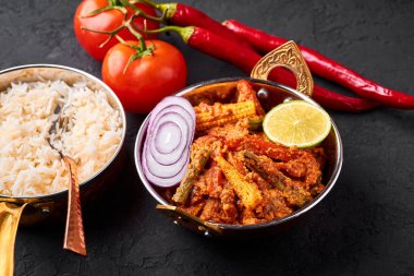 Bakır kadai 'de sebze Jalfrezi ve siyah tahta kaplamalı basmati pilavı. Jalfrezi, Hint mutfağı. Kızarmış sebze ve baharatlı domates sosu. Hint Yemeği.