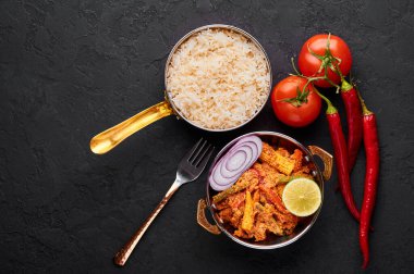 Bakır kadai 'de sebze Jalfrezi ve siyah tahta kaplamalı basmati pilavı. Jalfrezi, Hint mutfağı. Kızarmış sebze ve baharatlı domates sosu. Hint Yemeği.