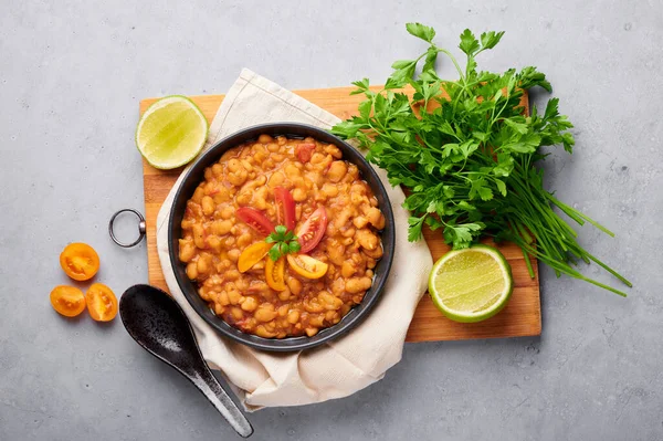 Ful Medames ya da Fava Beans gri arka planda siyah kasede. Foul Mudammas, Mısırlı, Lübnanlı, Suriyeli, Eritre asıllı, İsrail mutfağından pişirilmiş kimyon, domates, maydanoz ve fasulyeli kahvaltı tabağı.