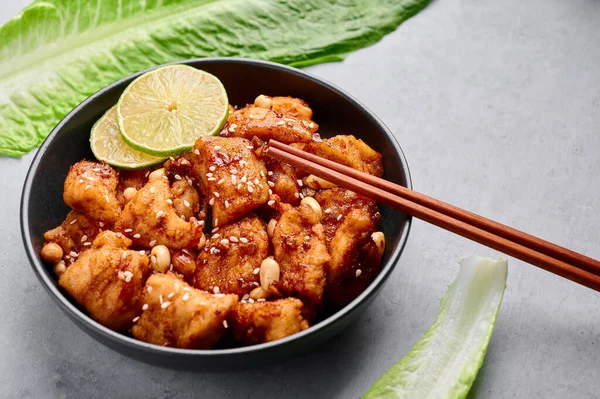 Kore usulü kızarmış tavuk Dakgangjeong siyah kasede gri beton arka planda. Dakgangjeong, tatlı soslu kızarmış tavuklu Kore mutfağı. Kore Yemeği