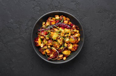 Kung Pao Paneer siyah arkaplanda. Kung Pao Paneer Çin yemeği Gong Bao 'nun paneer peyniri, fıstık, biber, sos ve soğanlı vejetaryen versiyonu. Üst Manzara. Boşluğu kopyala