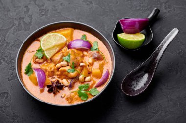 Arka planda siyah kâse içinde tavuk masajcısı körisi. Massaman Curry, Tayland mutfağında tavuk eti, patates, soğan ve birçok baharatla servis edilir. Tayland Yemeği.