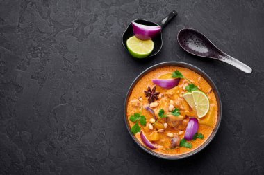 Arka planda siyah kâse içinde tavuk masajcısı körisi. Massaman Curry, Tayland mutfağında tavuk eti, patates, soğan ve birçok baharatla servis edilir. Tayland yemeği. Uzayı kopyala Üst görünüm
