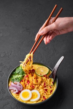 Ohn No Khao Swe siyah kasede, arka planda. Oh No Khao Suey hindistan cevizi sütü erişteli tavuk eti ve yumurtalı miyanmar çorbası. Birmanya yemeği.