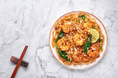 Beyaz mermer zemin üzerinde karides pedi bkz. Pad See Ew, Tayland mutfağında pilav, erişte, karides, soya ve istiridye sosu ve yeşillik. Tayland yemeği. Uzayı kopyala Üst görünüm