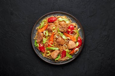 Pad Woon Sen ya da Tayland Pork Bardağı Erişte Kızartması. Siyah tabakta, arka planda. Pad Woon Sen, Tayland 'da cam erişte, et, domates, havuç, yumurta ve sostan oluşan bir yemek tabağıdır. Tayland Yemeği.