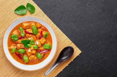 Beyaz tabakta, arka planda Tayland Panang Tavuk Köri 'si. Phanaeng Curry, Tayland mutfağı. İçinde tavuk, kaffir limon yaprağı, kırmızı köri sosu ve sebze var. Tayland yemeği. Boşluğu kopyala