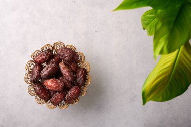 Gri beton arka planda bronz kaplamalı meyveler ya da Kurma. Randevular Ramazan yemeğidir. Ramazan iftar yiyeceği.