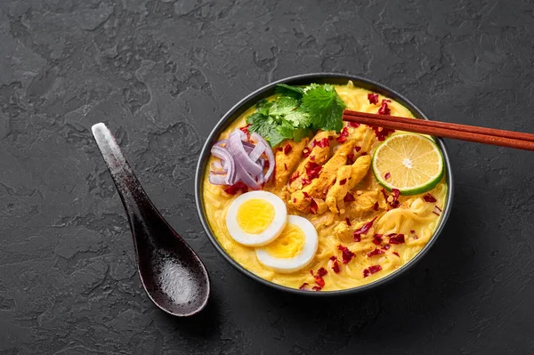 Ohn No Khao Swe siyah kasede, arka planda. Oh No Khao Suey hindistan cevizi sütü erişteli tavuk eti ve yumurtalı miyanmar çorbası. Birmanya yemeği. Boşluğu kopyala