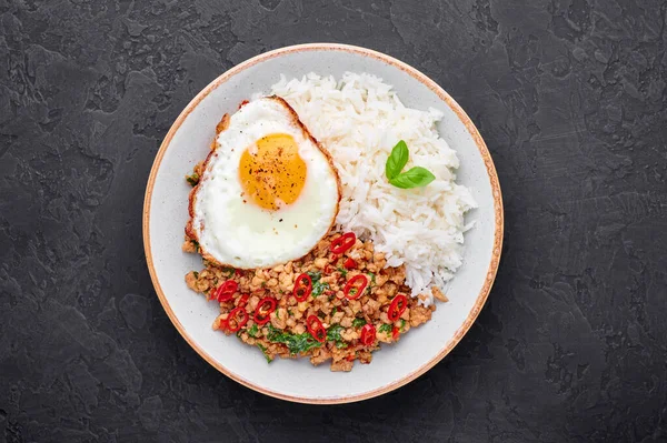 Pad Krapow Gai - Thai Basil Chicken with Rice and fried Egg black slate background. Pad Krapow is Thai cuisine dish with minced chicken or pork meat, basil, soy and oyster sauces. Thai Food Copy space