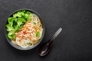 Guay Tiew Gai Cheek ya da Tayland Tavuğu Erişte Çorbası. Siyah kasede, arka planda. Guay Tiew Gai, Tayland usulü erişteli, tavuklu, soslu, yeşillikli çorba. Tayland yemeği. Boşluğu kopyala.