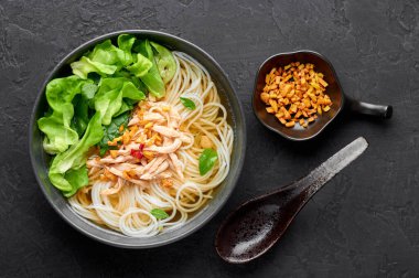 Guay Tiew Gai Cheek ya da Tayland Tavuğu Erişte Çorbası. Siyah kasede, arka planda. Guay Tiew Gai, Tayland usulü erişteli, tavuklu, soslu, yeşillikli çorba. Tayland yemeği. Üst görünüm