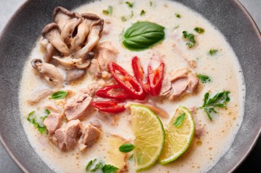 Tom Kha Gai ya da Tayland Hindistancevizi Tavuk Çorbası, arka planda, mat gri kasede. Tom Kha Gai, Hindistan cevizi sütü, tavuk, galangal, limon otu, mantar ve limonlu Tayland mutfağı. Tayland Yemeği