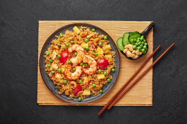 Tayland Pineapple Fried Rice ya da Kao Pad Sapparod siyah bir tabakta, arka planda. Kao Pad Sapparod bir Tayland mutfağı tabağıdır. Tayland yemeği. Asya yemekleri. Üst görünüm