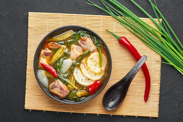 Sinigang na Baboy ya da Filipinli Pork Et Çorbası. Siyah kasede, arka planda. Sinigang, et, bamia, daikon, ıspanak ve balık soslu bir Filipin mutfağıdır. Filipin yemeği. Asya Yemekleri