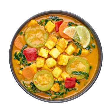 Beyaz arka planda izole edilmiş soya peynirli sarı sebzeli Tayland körisi. Tofulu, kabaklı, dolmalık biberli, ıspanaklı, havuçlu vejetaryen Thai Curry. Tayland yemeği. Hint sebzeli köri. Üst görünüm